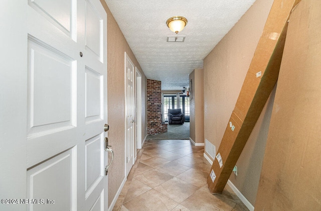 hall with brick wall, a textured ceiling, and light carpet