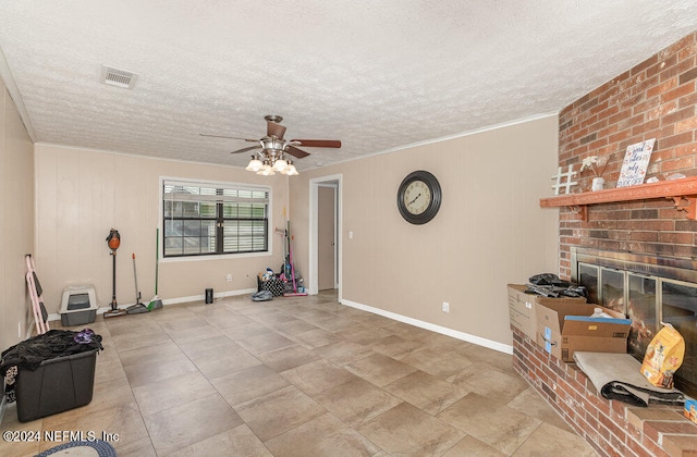 interior space with ceiling fan, crown molding, brick wall, a textured ceiling, and a brick fireplace