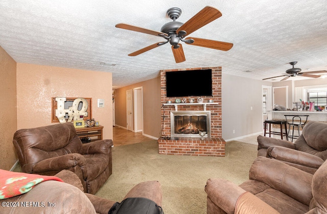 living room featuring a textured ceiling, light carpet, a brick fireplace, and ceiling fan