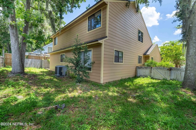 rear view of house featuring central AC unit and a lawn