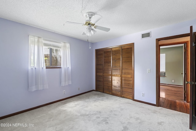 unfurnished bedroom featuring a textured ceiling, carpet floors, a closet, and ceiling fan