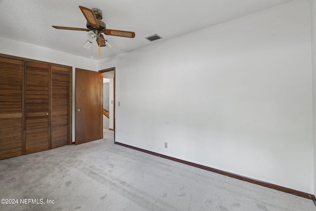 unfurnished bedroom with light colored carpet, a closet, and ceiling fan