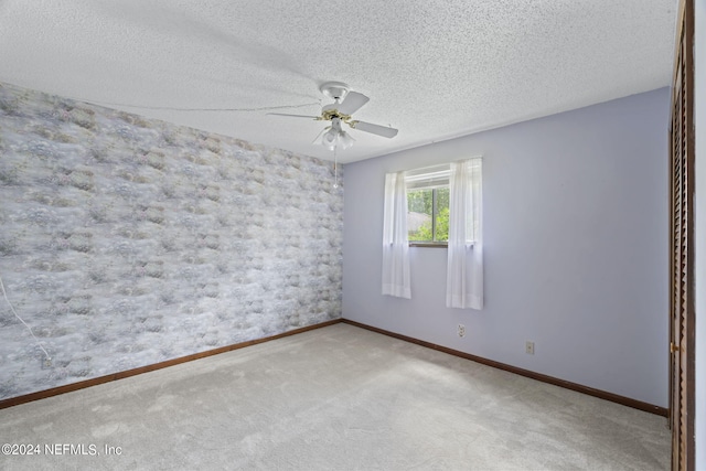 carpeted empty room with ceiling fan and a textured ceiling