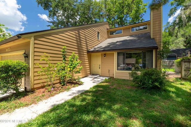 back of property with a garage and a lawn