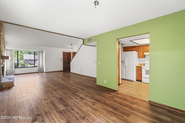 unfurnished living room with a fireplace, dark wood-type flooring, and vaulted ceiling