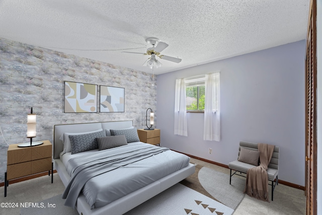 bedroom with ceiling fan, light carpet, and a textured ceiling