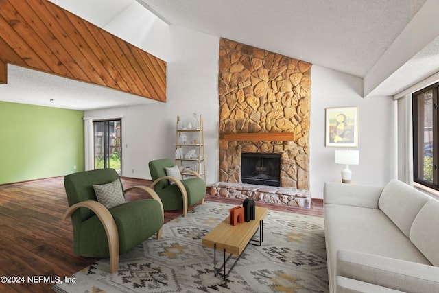 living room with hardwood / wood-style flooring, lofted ceiling, a textured ceiling, and a fireplace