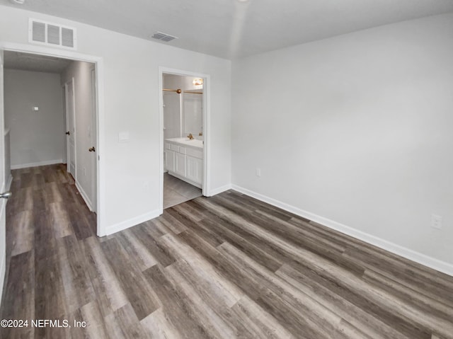 unfurnished bedroom with dark hardwood / wood-style flooring and ensuite bath