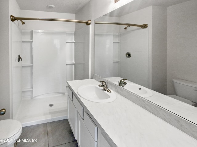 bathroom featuring tile patterned floors, toilet, vanity, and walk in shower