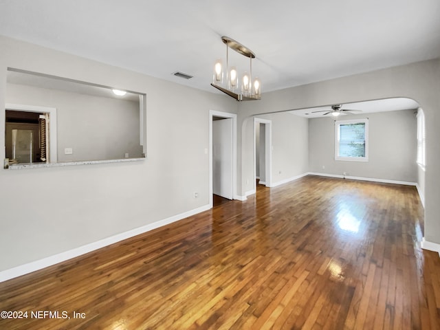 unfurnished living room with ceiling fan with notable chandelier and dark hardwood / wood-style flooring