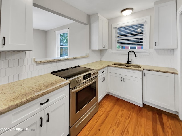 kitchen with white cabinetry, light hardwood / wood-style floors, sink, tasteful backsplash, and stainless steel electric stove