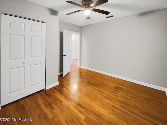 unfurnished bedroom featuring a closet, wood-type flooring, and ceiling fan