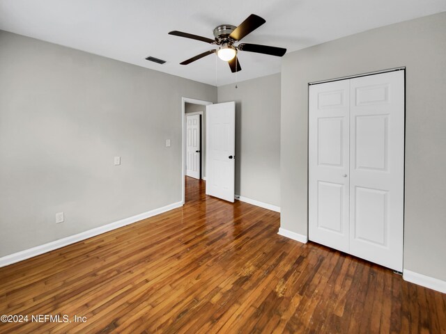 unfurnished bedroom with a closet, ceiling fan, and dark wood-type flooring