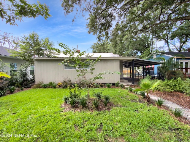 rear view of house with a lawn and a carport