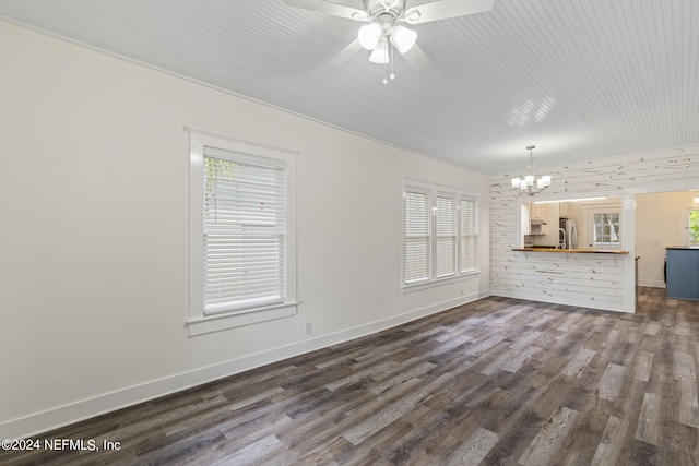 unfurnished living room featuring dark wood-style floors, ceiling fan with notable chandelier, a sink, and baseboards