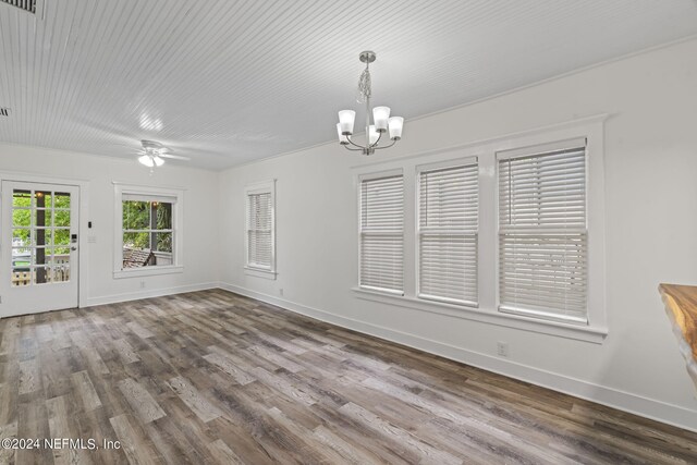 unfurnished dining area featuring ceiling fan with notable chandelier, baseboards, and wood finished floors