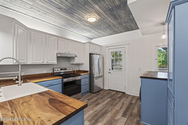 kitchen with blue cabinetry, butcher block counters, appliances with stainless steel finishes, white cabinets, and under cabinet range hood