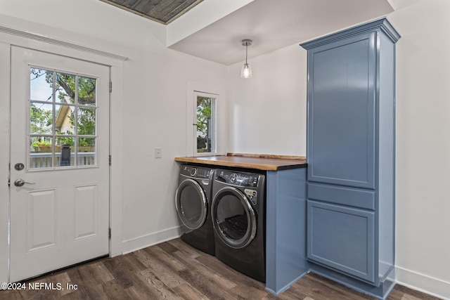 clothes washing area featuring dark wood-type flooring, a wealth of natural light, cabinet space, and washing machine and clothes dryer