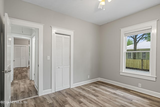 unfurnished bedroom with attic access, a closet, baseboards, and wood finished floors