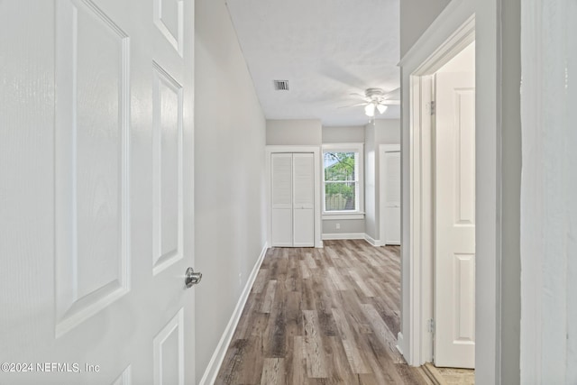 corridor featuring light wood-style floors, visible vents, and baseboards