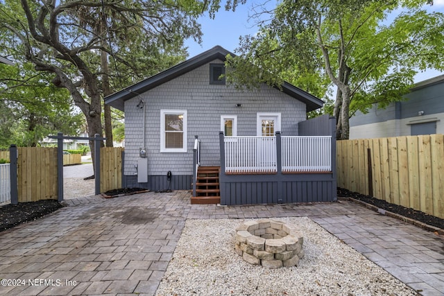 rear view of house with a deck, an outdoor fire pit, and a fenced backyard