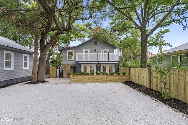 view of front of home featuring french doors, fence, a balcony, and stairs