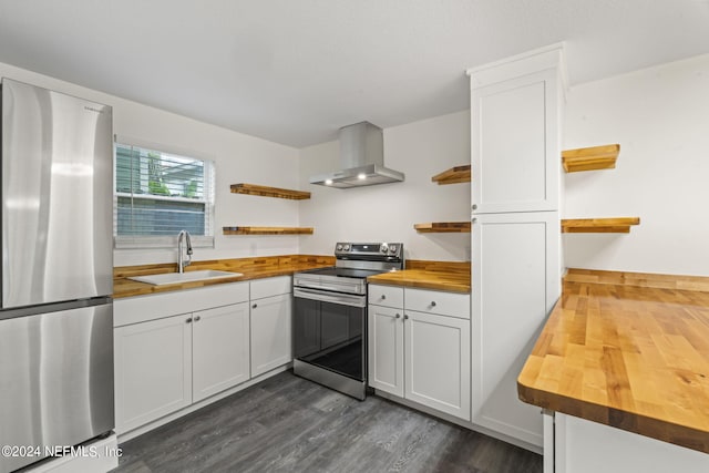 kitchen with wood counters, stainless steel appliances, wall chimney range hood, white cabinetry, and open shelves