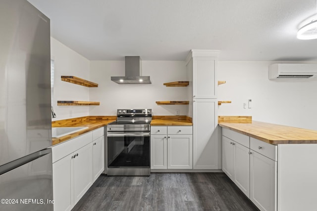 kitchen featuring butcher block countertops, an AC wall unit, wall chimney range hood, and appliances with stainless steel finishes