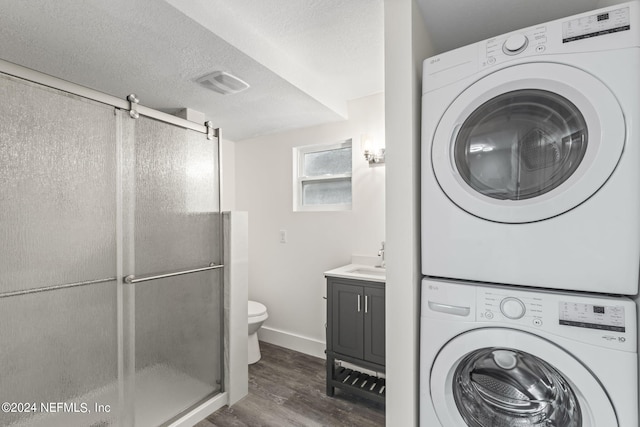 bathroom featuring stacked washer / drying machine, visible vents, an enclosed shower, a textured ceiling, and wood finished floors