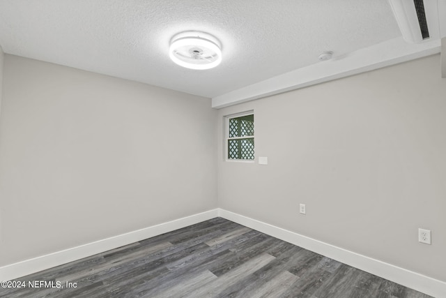 spare room featuring a textured ceiling, baseboards, and dark wood-style flooring