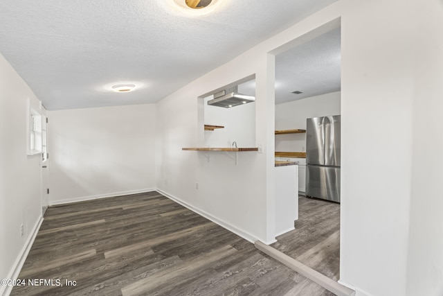 interior space with baseboards, dark wood finished floors, and a textured ceiling