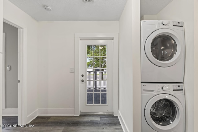 clothes washing area with dark wood-type flooring, laundry area, baseboards, and stacked washing maching and dryer