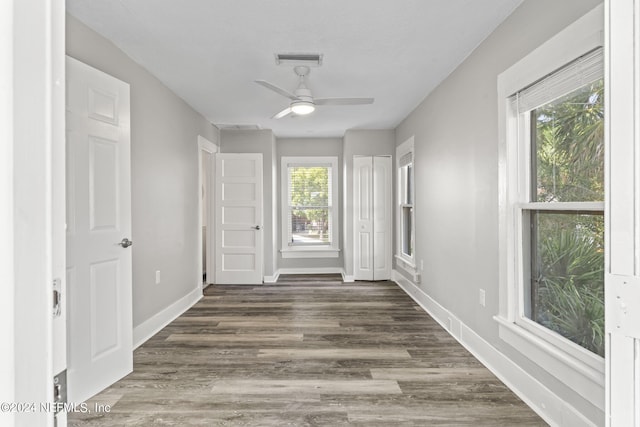 interior space featuring dark wood-style floors, a ceiling fan, visible vents, and baseboards