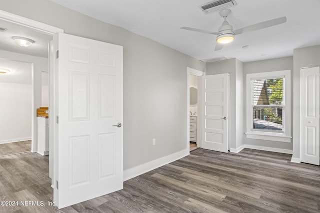 unfurnished bedroom featuring a ceiling fan, dark wood finished floors, visible vents, and baseboards