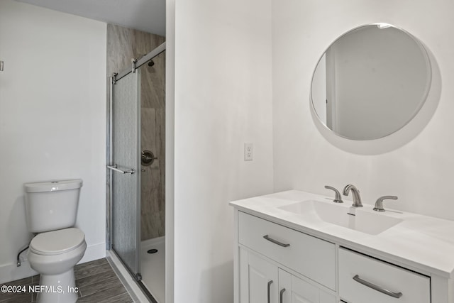 full bathroom with toilet, a shower stall, vanity, wood finished floors, and baseboards