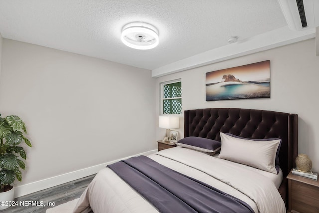 bedroom with baseboards, dark wood finished floors, and a textured ceiling