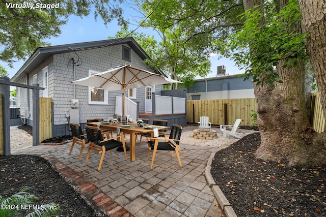 rear view of property with a patio, an outdoor fire pit, outdoor dining area, and fence