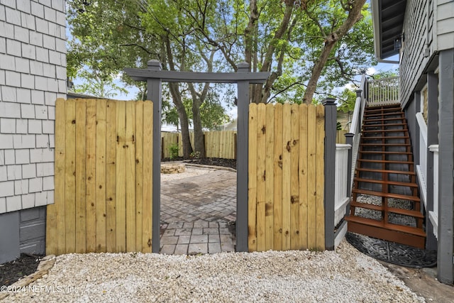 view of gate with fence, stairway, and a patio