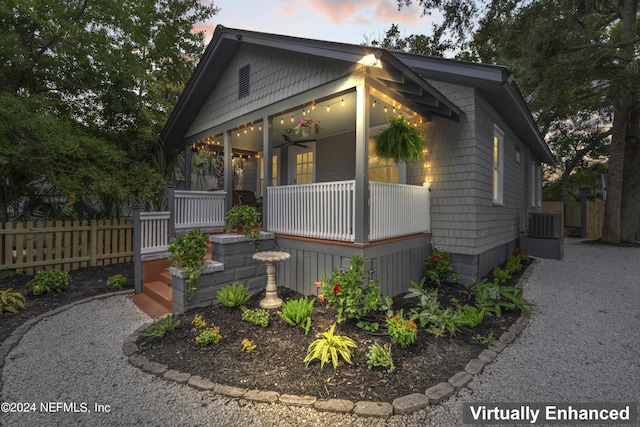 view of front facade with a porch, fence, central AC unit, and a ceiling fan