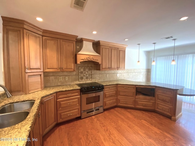 kitchen featuring pendant lighting, premium range hood, electric stove, sink, and built in microwave