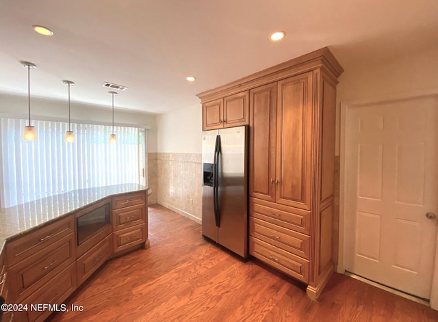 kitchen featuring built in microwave, light stone counters, stainless steel refrigerator with ice dispenser, dark hardwood / wood-style floors, and pendant lighting