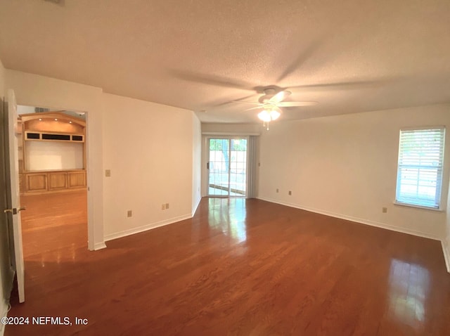 unfurnished room with a textured ceiling, ceiling fan, and dark wood-type flooring