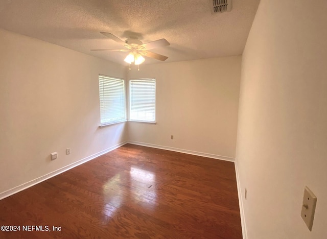 empty room featuring ceiling fan, dark wood-type flooring, and a textured ceiling