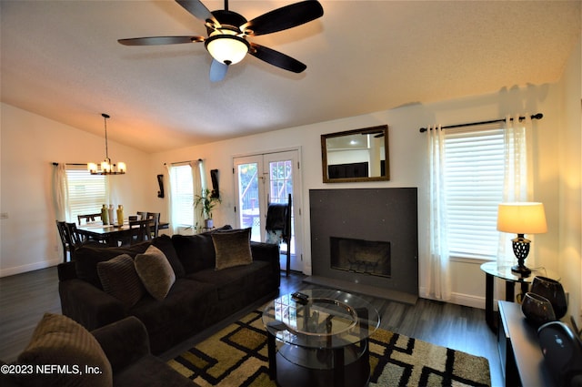 living room with ceiling fan with notable chandelier, vaulted ceiling, plenty of natural light, and dark wood-type flooring