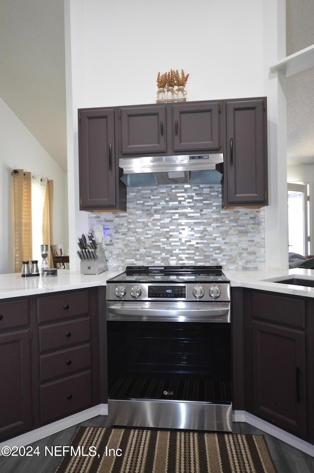 kitchen featuring backsplash, dark brown cabinetry, vaulted ceiling, sink, and stainless steel electric range