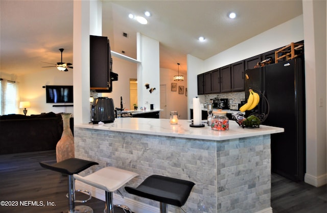 kitchen with black fridge, kitchen peninsula, a breakfast bar area, and tasteful backsplash