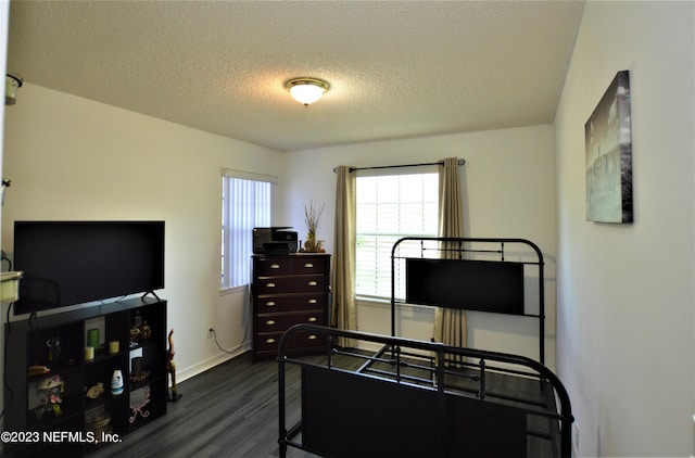 bedroom with dark hardwood / wood-style flooring and a textured ceiling