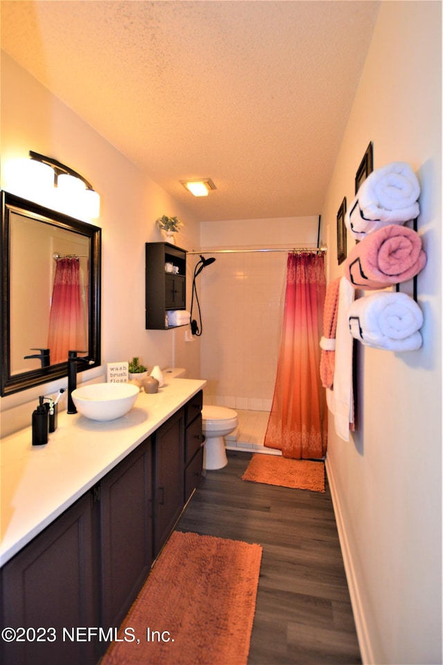 bathroom featuring vanity, a textured ceiling, hardwood / wood-style flooring, toilet, and curtained shower