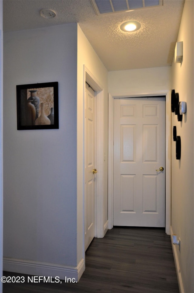 hallway featuring a textured ceiling and dark wood-type flooring