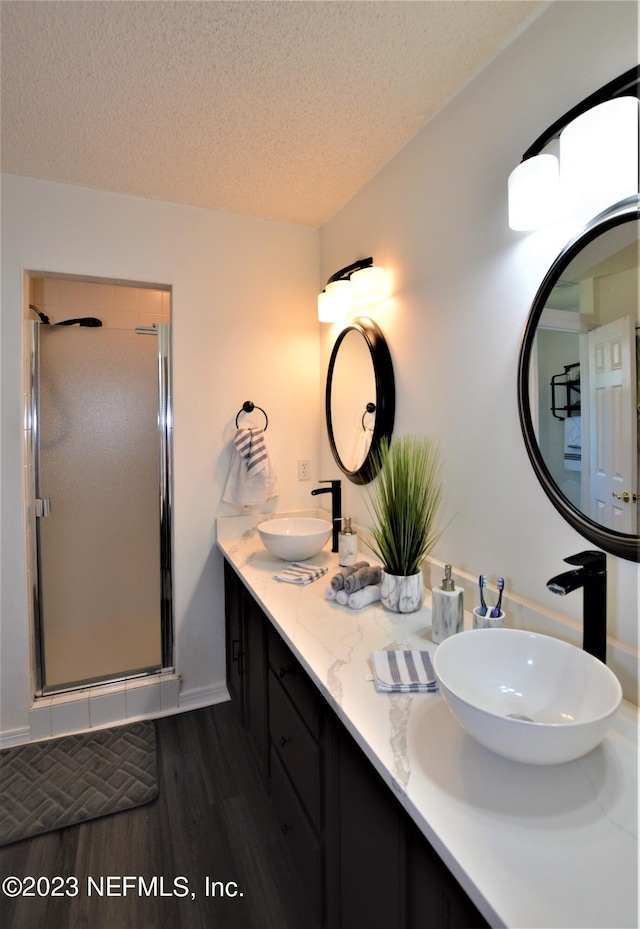 bathroom featuring a shower with door, vanity, a textured ceiling, and hardwood / wood-style flooring